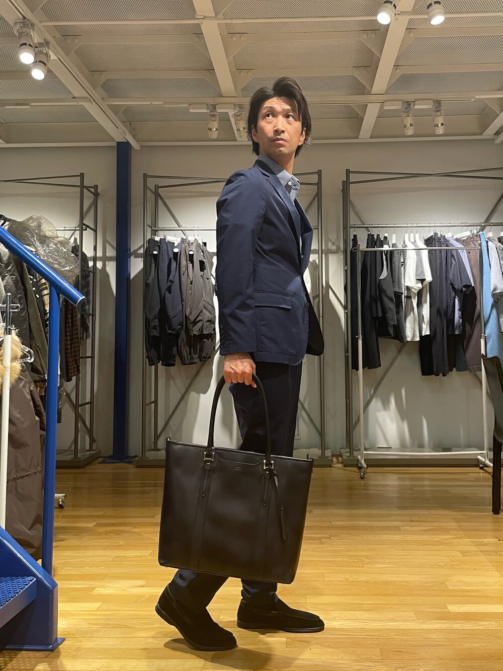 ブラック系のトートバッグ、ブルー系のポロシャツ、ブルー系のテーラードジャケットを着用したメンズの春コーディネートの2枚目の写真
