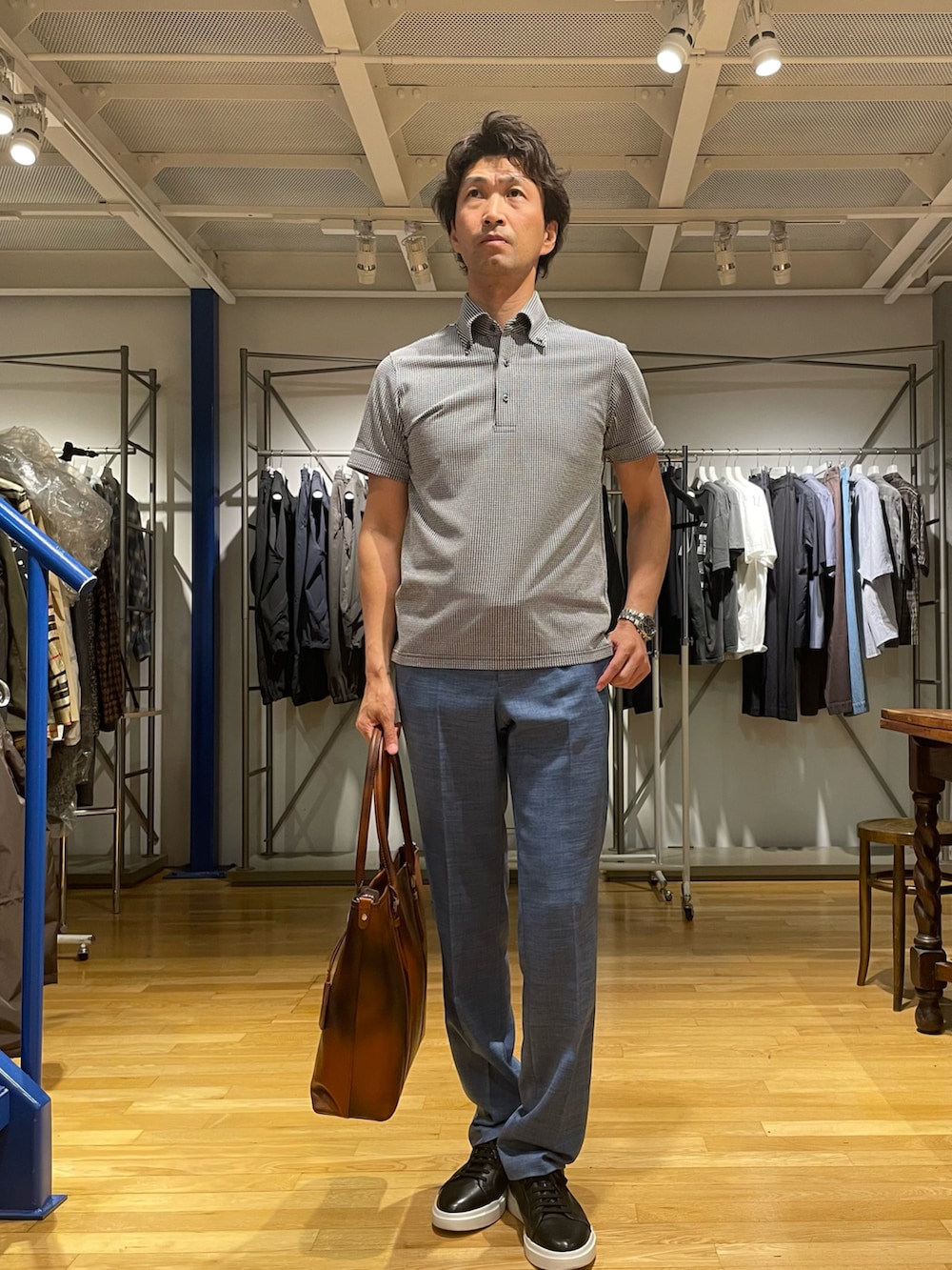 ブルー系のポロシャツ、ブルー系のスラックス、ブラック系のスニーカーを着用したメンズの春コーディネートの2枚目の写真