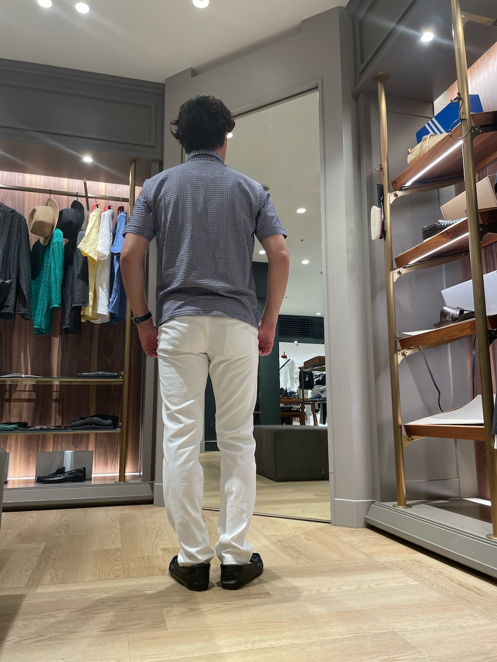 ブルー系のポロシャツ、ホワイト系のその他パンツ、ブラック系のモカシン/デッキシューズを着用したメンズの夏コーディネートの2枚目の写真
