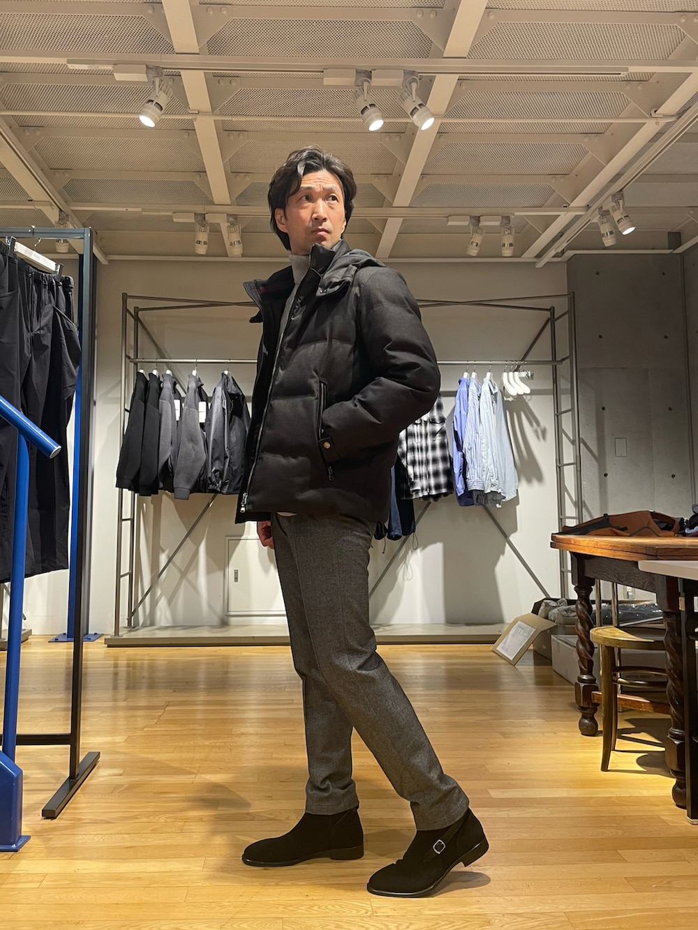 ブラック系のダウンジャケット/コート、グレー系のニット/セーター、グレー系のスラックスを着用したメンズの秋コーディネートの2枚目の写真