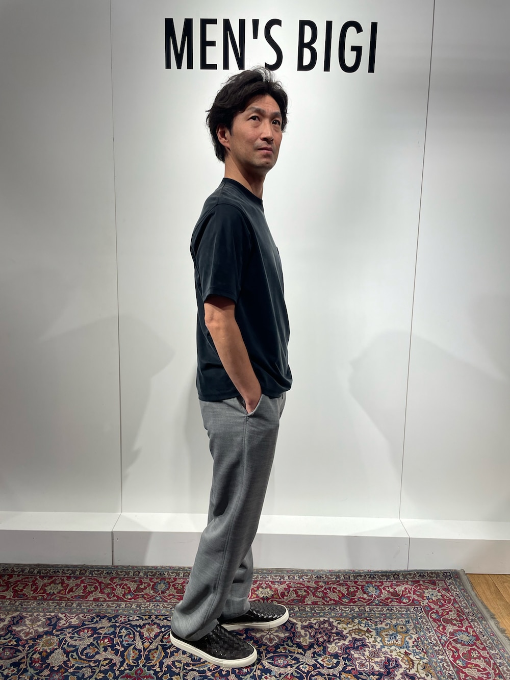 ブラック系のTシャツ/カットソー、グレー系のその他パンツ、ブラウン系のスリッポンを着用したメンズの春コーディネートの2枚目の写真
