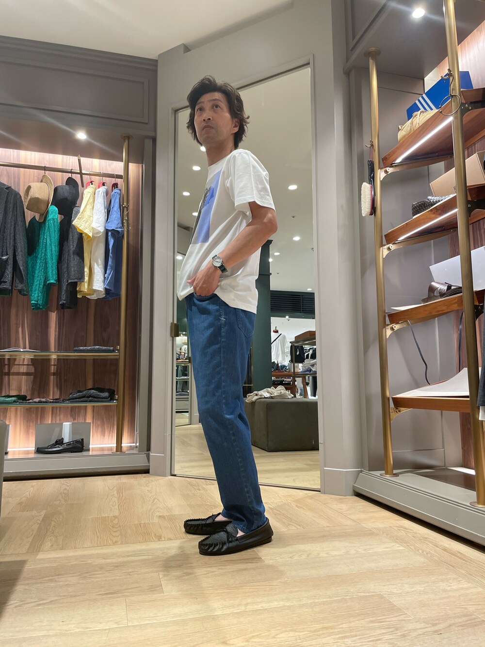 ホワイト系のTシャツ/カットソー、ブルー系のデニムパンツ、ブラック系のモカシン/デッキシューズを着用したメンズの夏コーディネートの2枚目の写真