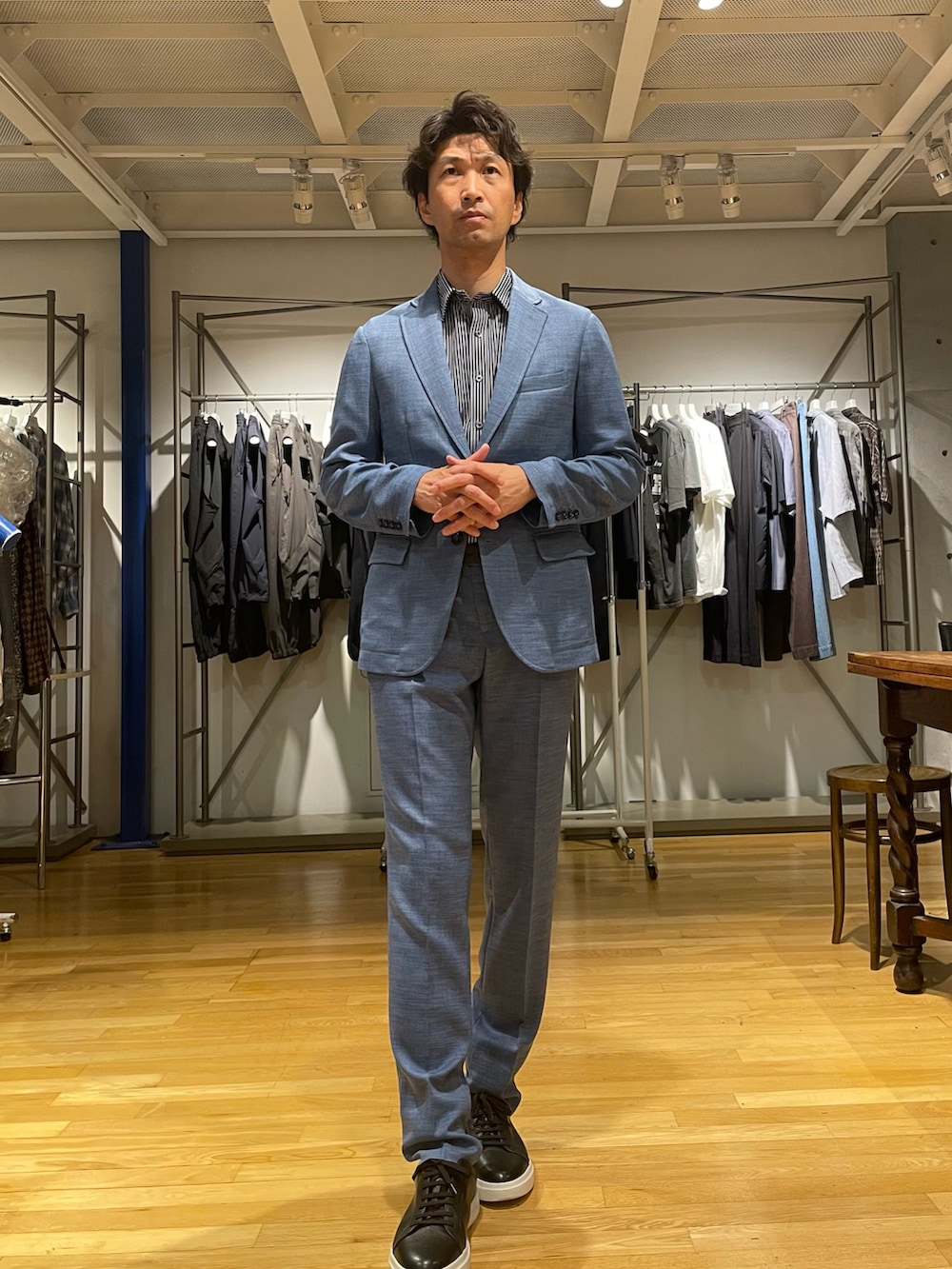 ブルー系のテーラードジャケット、ブルー系のスラックス、ブラック系のスニーカーを着用したメンズの春コーディネートの2枚目の写真