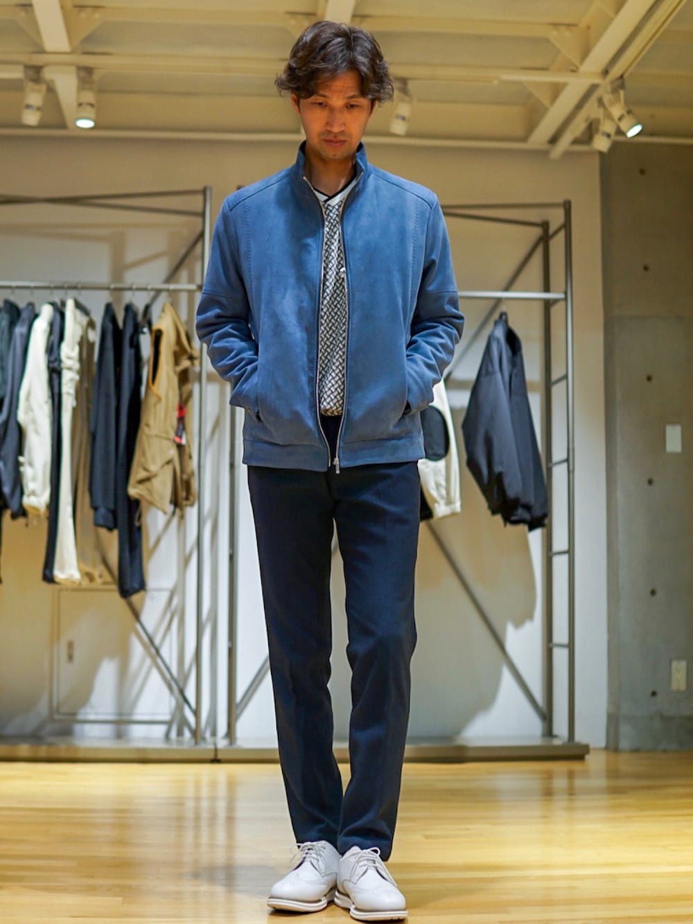 ベージュ系のブルゾン、ブルー系のスラックス、ホワイト系のスニーカーを着用したメンズの秋コーディネートの2枚目の写真