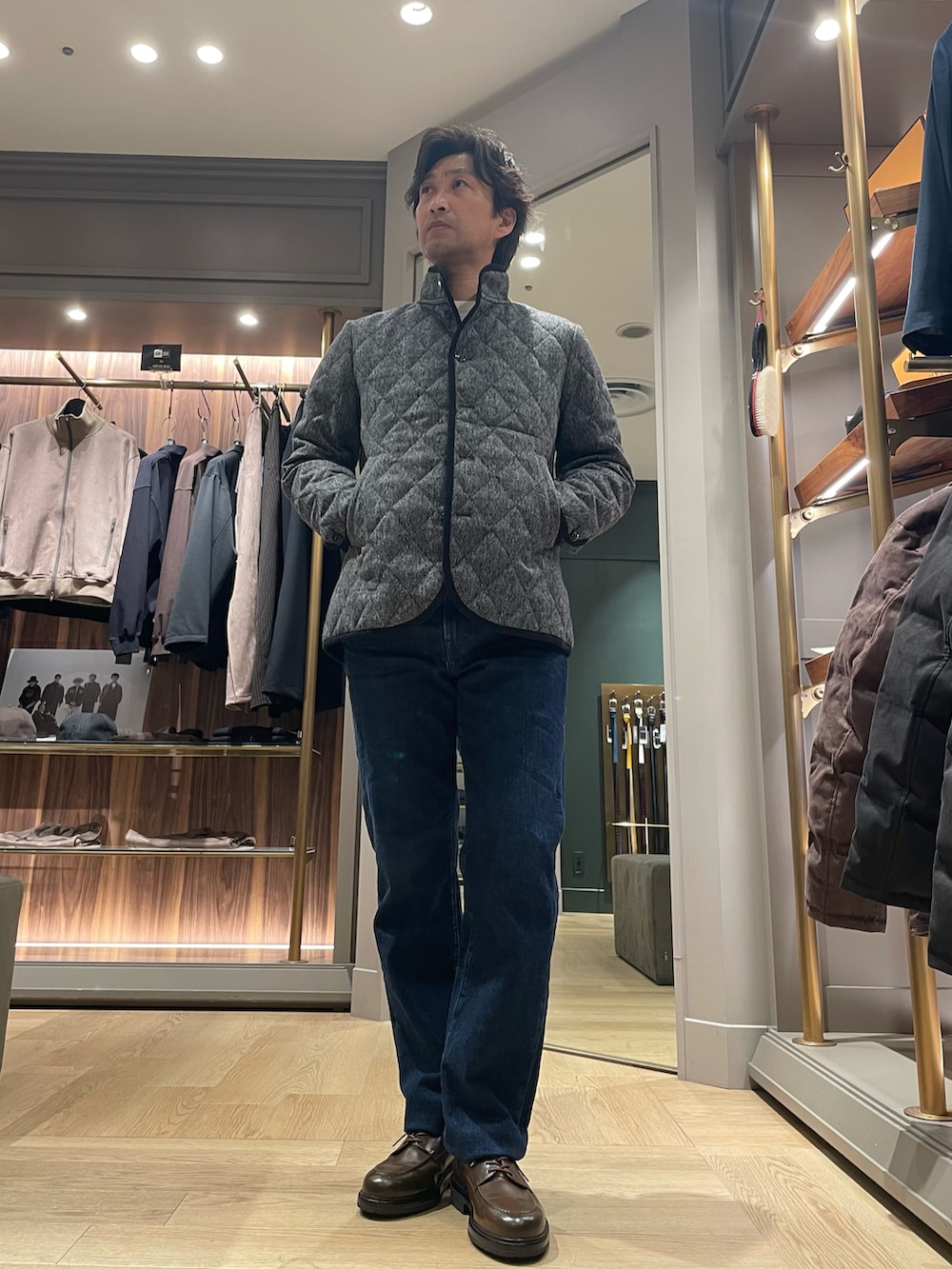 グレー系のブルゾン、ブルー系のデニムパンツ、ブラウン系のドレスシューズを着用したメンズの冬コーディネートの2枚目の写真