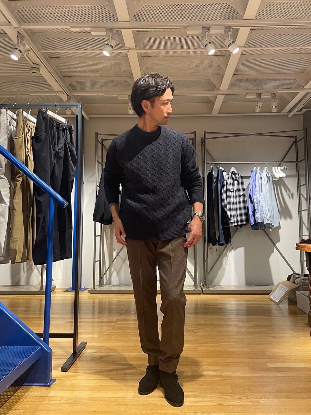 ブラック系のニット/セーター、ブラウン系のスラックス、ブラック系のブーツを着用したメンズの冬コーディネートの2枚目の写真