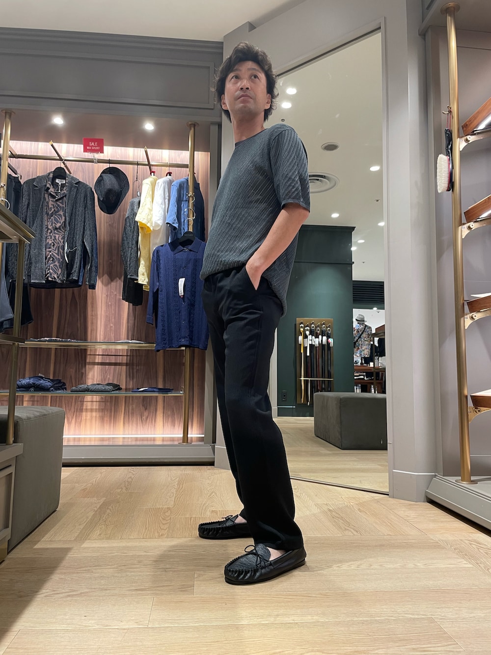 グリーン系のTシャツ/カットソー、ブラック系のその他パンツ、ブラック系のモカシン/デッキシューズを着用したメンズの夏コーディネートの3枚目の写真