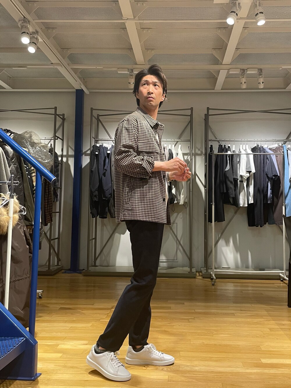 ブラウン系のブルゾン、ブルー系のスラックス、ホワイト系のスニーカーを着用したメンズの春コーディネートの2枚目の写真