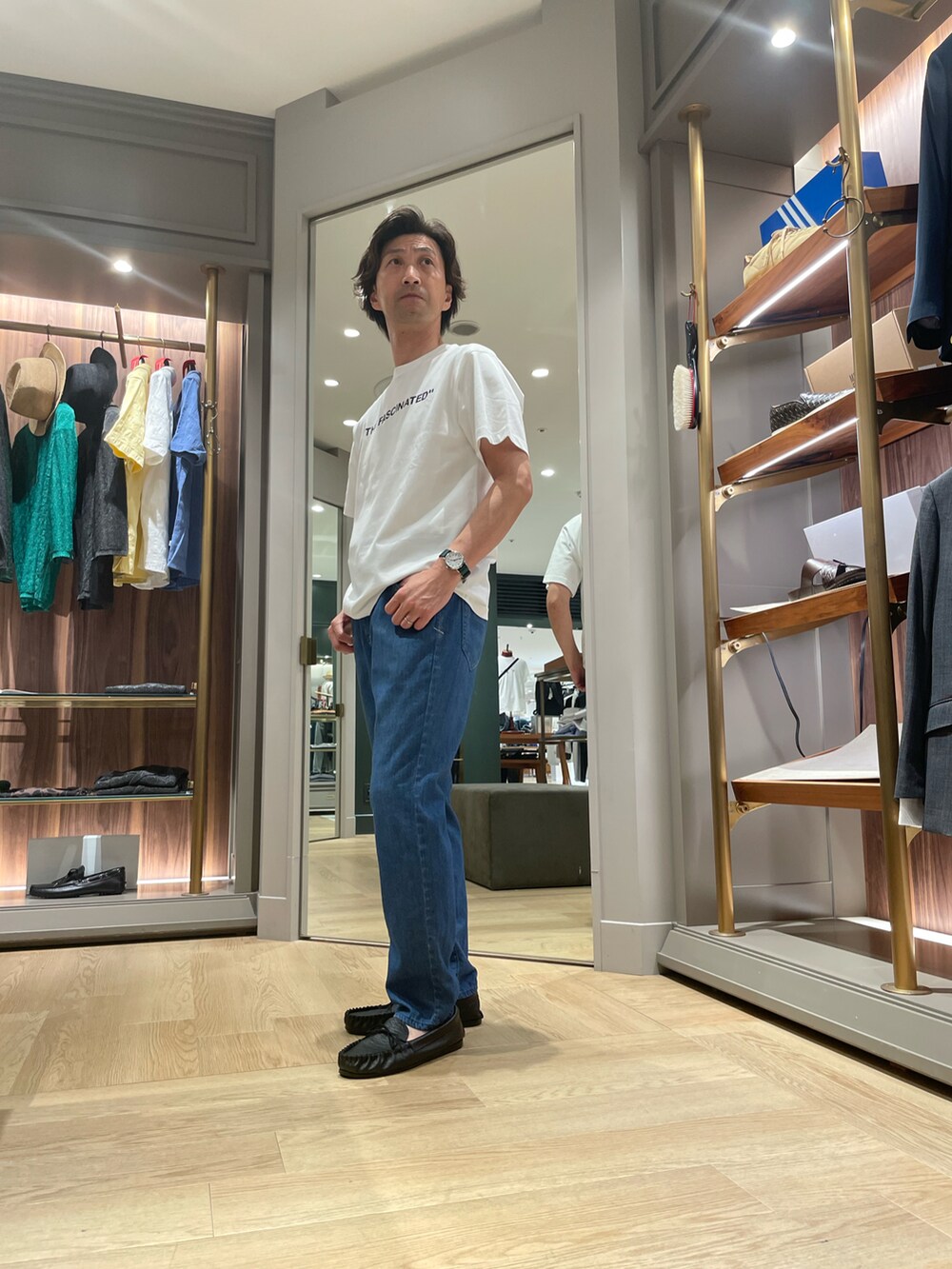 ホワイト系のTシャツ/カットソー、ブルー系のデニムパンツ、ブラック系のモカシン/デッキシューズを着用したメンズの夏コーディネートの2枚目の写真