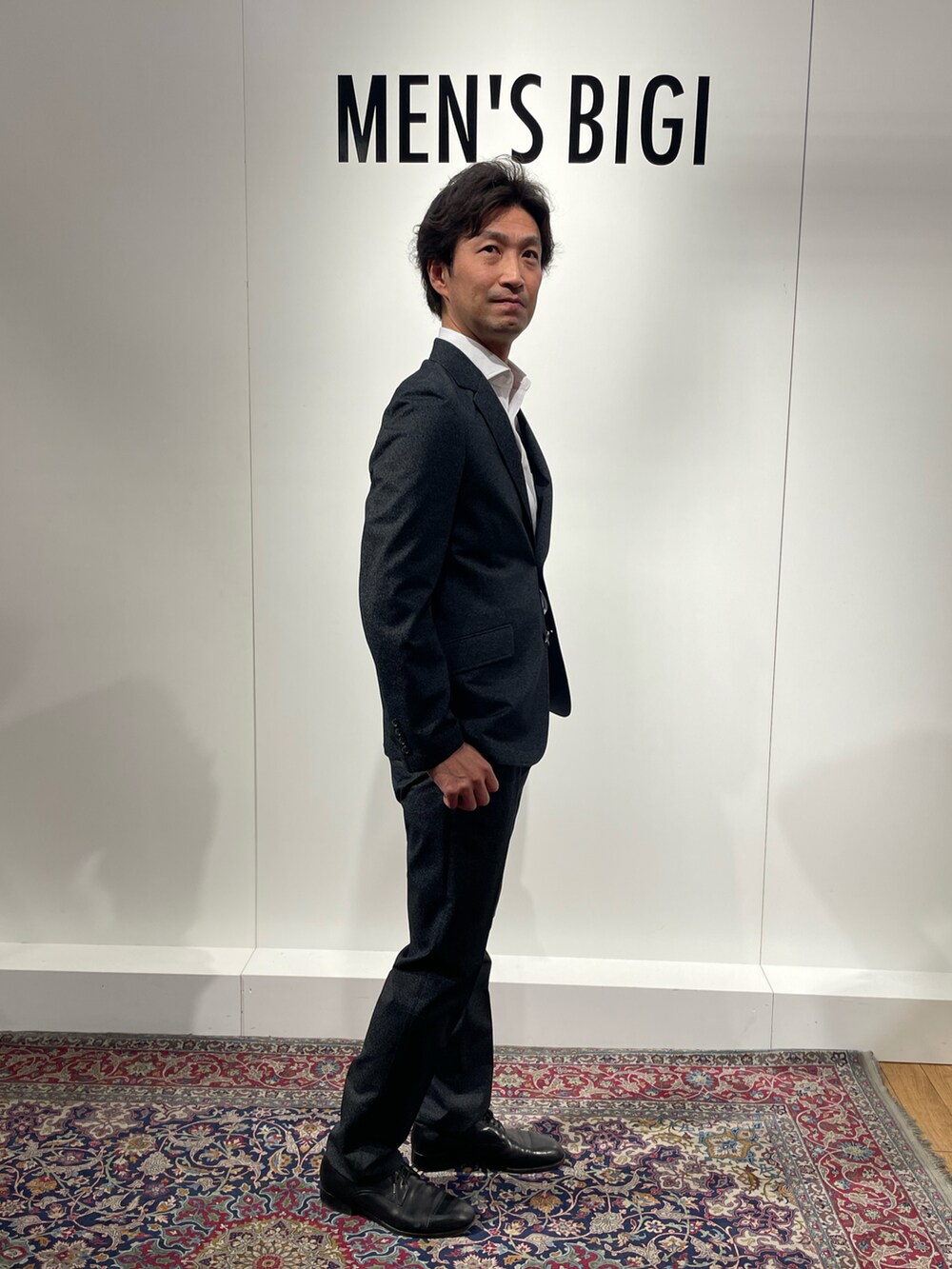 ホワイト系のビジネスシャツ、ブラック系のテーラードジャケット、ブラック系のスラックスを着用したメンズの冬コーディネートの3枚目の写真