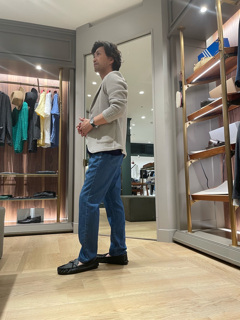 ホワイト系のテーラードジャケット、ブラック系のTシャツ/カットソー、ブルー系のデニムパンツを着用したメンズの夏コーディネートの2枚目の写真