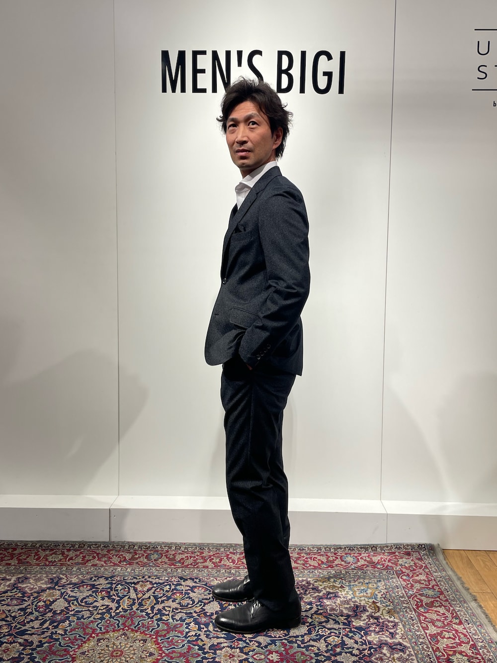 ホワイト系のビジネスシャツ、ブラック系のテーラードジャケット、ブラック系のスラックスを着用したメンズの冬コーディネートの2枚目の写真