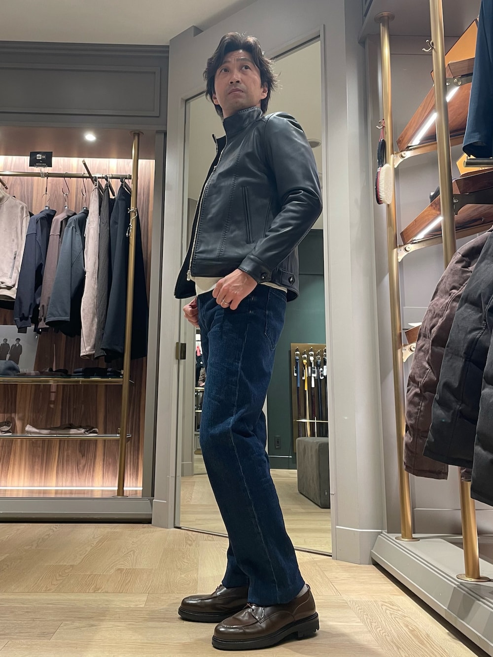 ブルー系のデニムパンツ、ブラウン系のドレスシューズ、ホワイト系のニット/セーターを着用したメンズの冬コーディネートの2枚目の写真