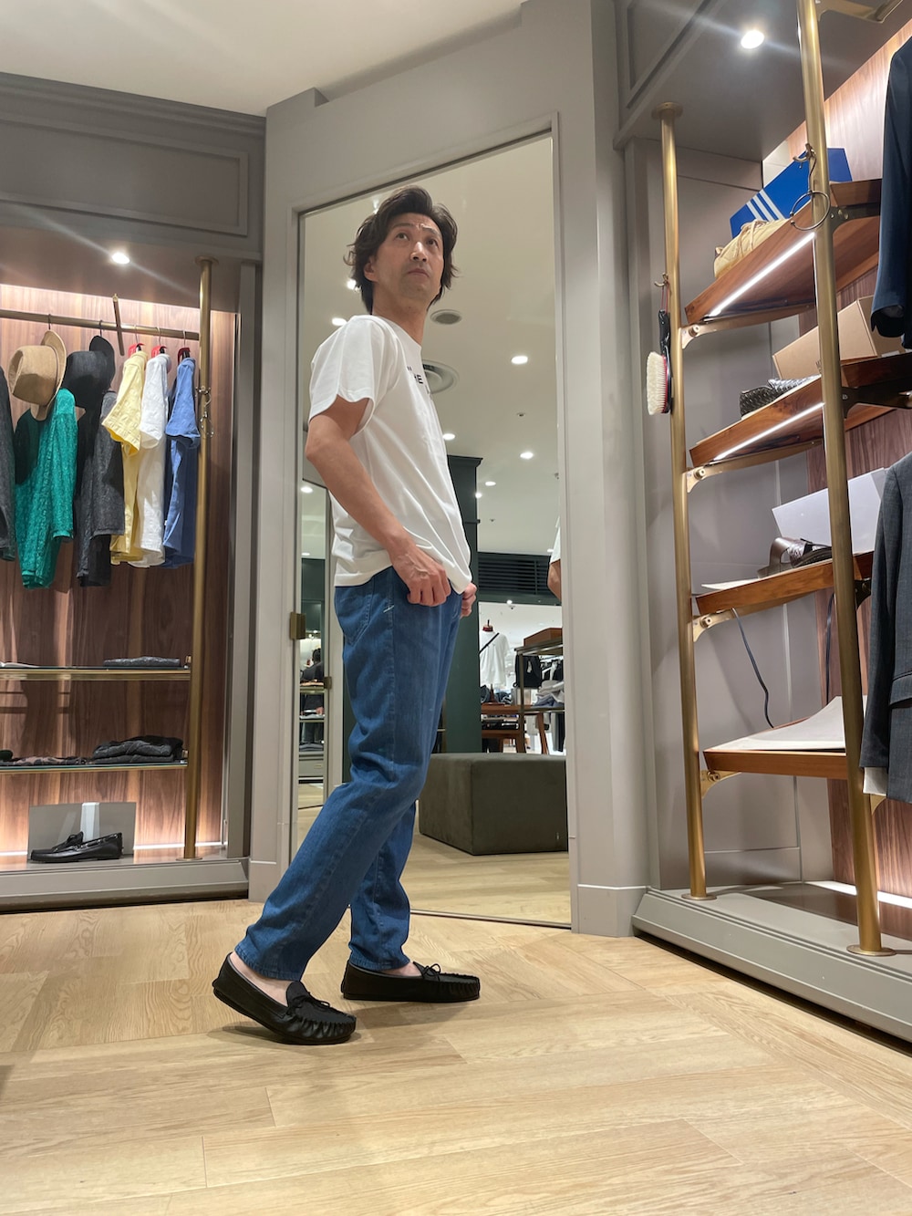 ホワイト系のTシャツ/カットソー、ブルー系のデニムパンツ、ブラック系のモカシン/デッキシューズを着用したメンズの夏コーディネートの4枚目の写真