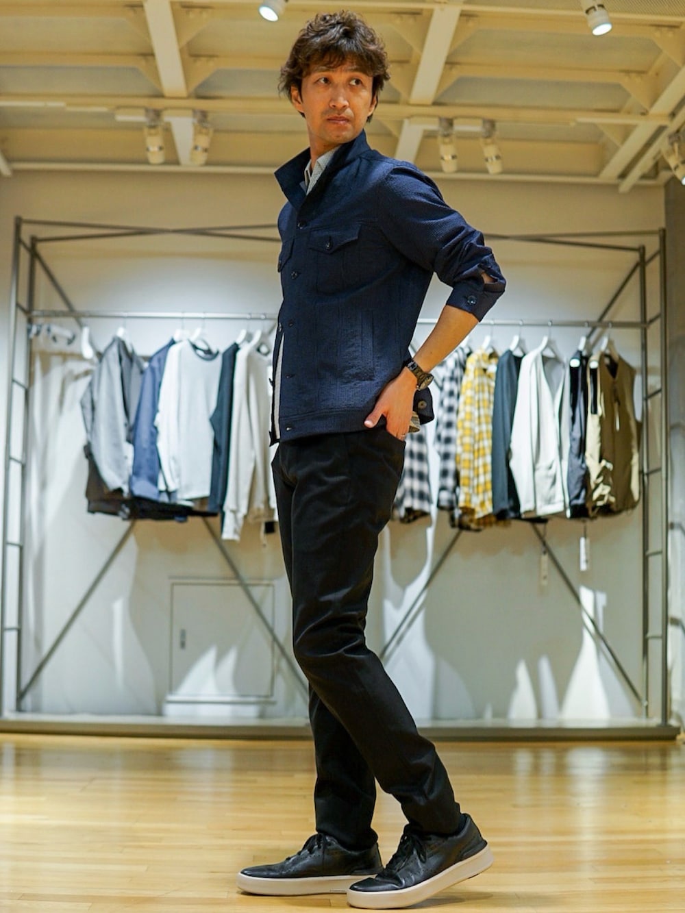 ブルー系のブルゾン、ブラック系のスラックス、ブラック系のスニーカーを着用したメンズの春コーディネートの2枚目の写真