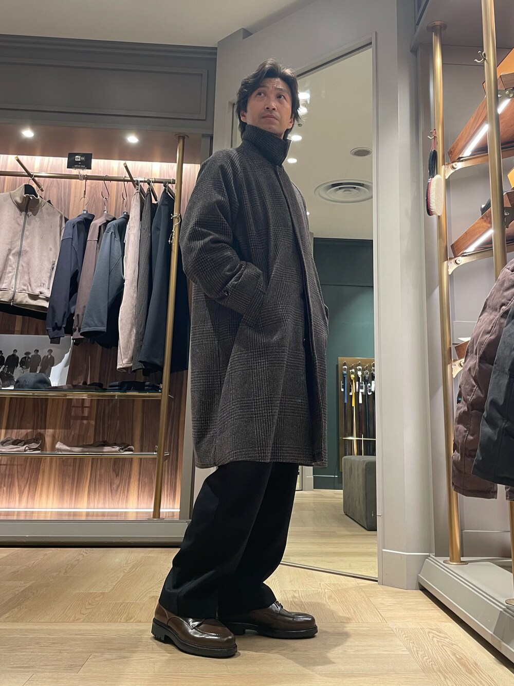 ブラウン系のダウンジャケット/コート、ブラック系のスラックス、ブラウン系のドレスシューズを着用したメンズの冬コーディネートの2枚目の写真