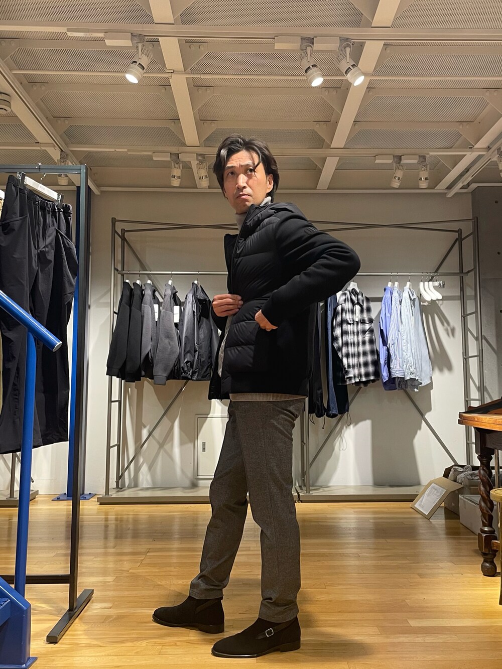 グレー系のニット/セーター、グレー系のスラックス、ブラック系のブーツを着用したメンズの秋コーディネートの2枚目の写真