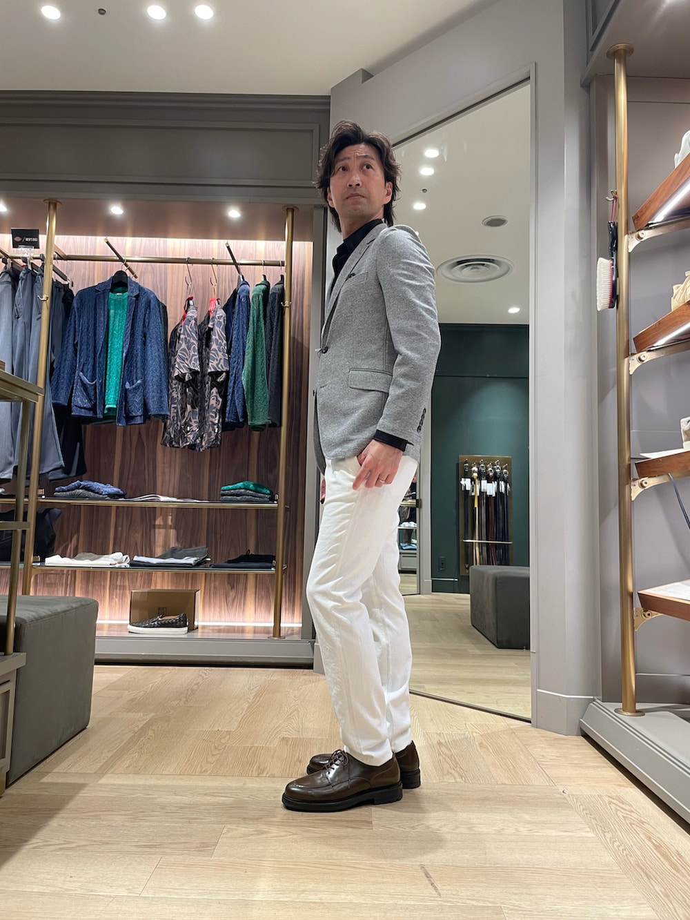 グレー系のテーラードジャケット、ホワイト系のその他パンツ、ブラウン系のドレスシューズを着用したメンズの春コーディネートの2枚目の写真