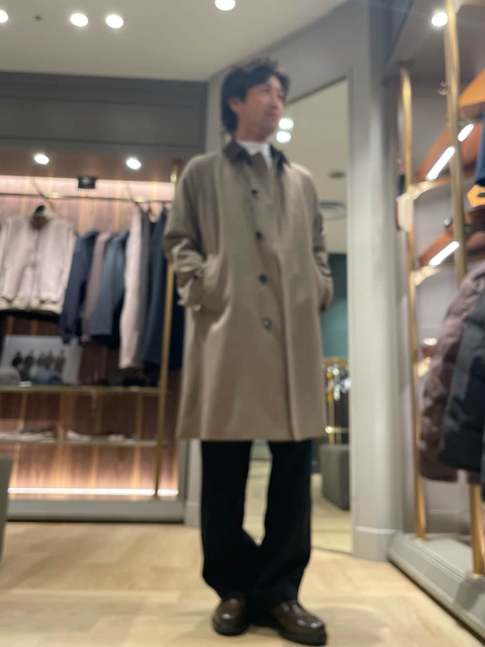 ブラウン系のトレンチコート、ブラック系のスラックス、ブラウン系のドレスシューズを着用したメンズの冬コーディネートの2枚目の写真