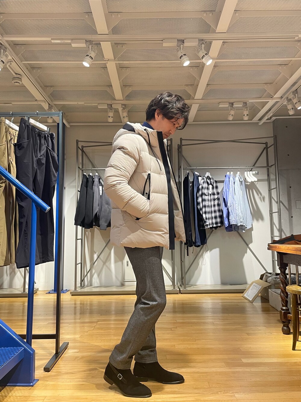 ブラック系のダウンジャケット/コート、ブルー系のニット/セーター、グレー系のスラックスを着用したメンズの冬コーディネートの2枚目の写真