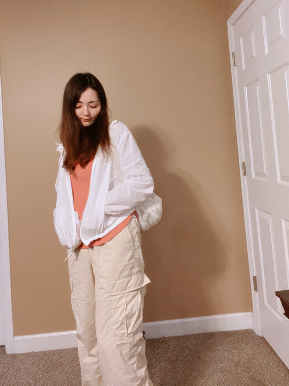 ホワイト系のマウンテンパーカー、グレー系のバッグ、オレンジ系のシャツ/ブラウスを着用したレディースの冬コーディネートの3枚目の写真