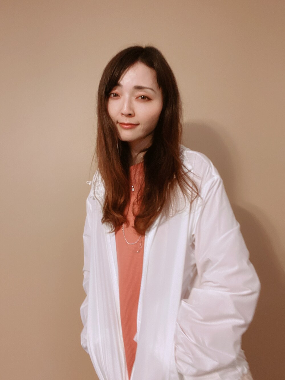 ホワイト系のマウンテンパーカー、グレー系のバッグ、オレンジ系のシャツ/ブラウスを着用したレディースの冬コーディネートの4枚目の写真