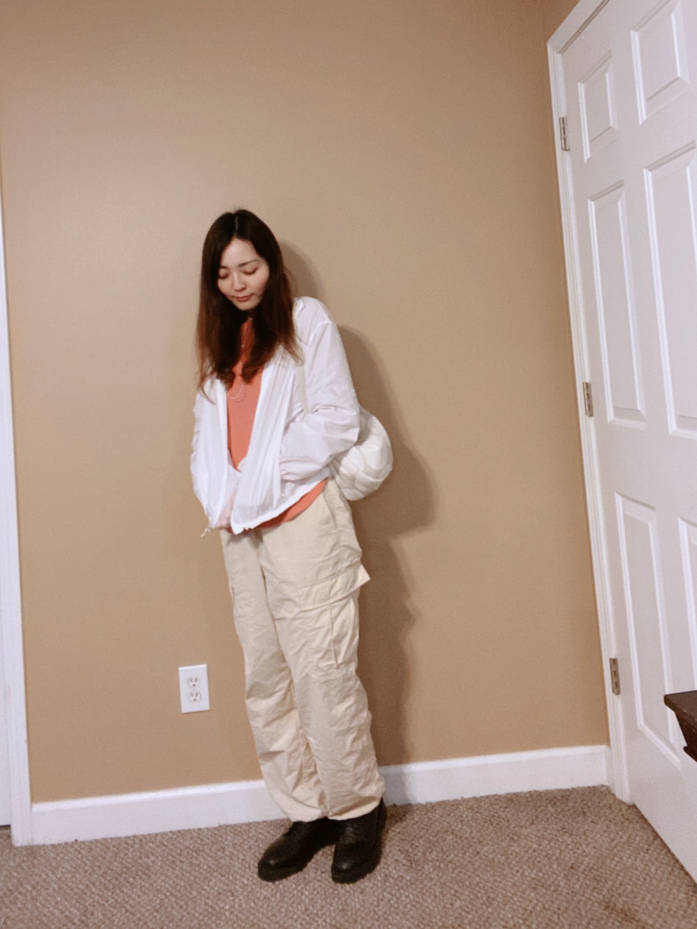 ホワイト系のマウンテンパーカー、グレー系のバッグ、オレンジ系のシャツ/ブラウスを着用したレディースの冬コーディネートの2枚目の写真