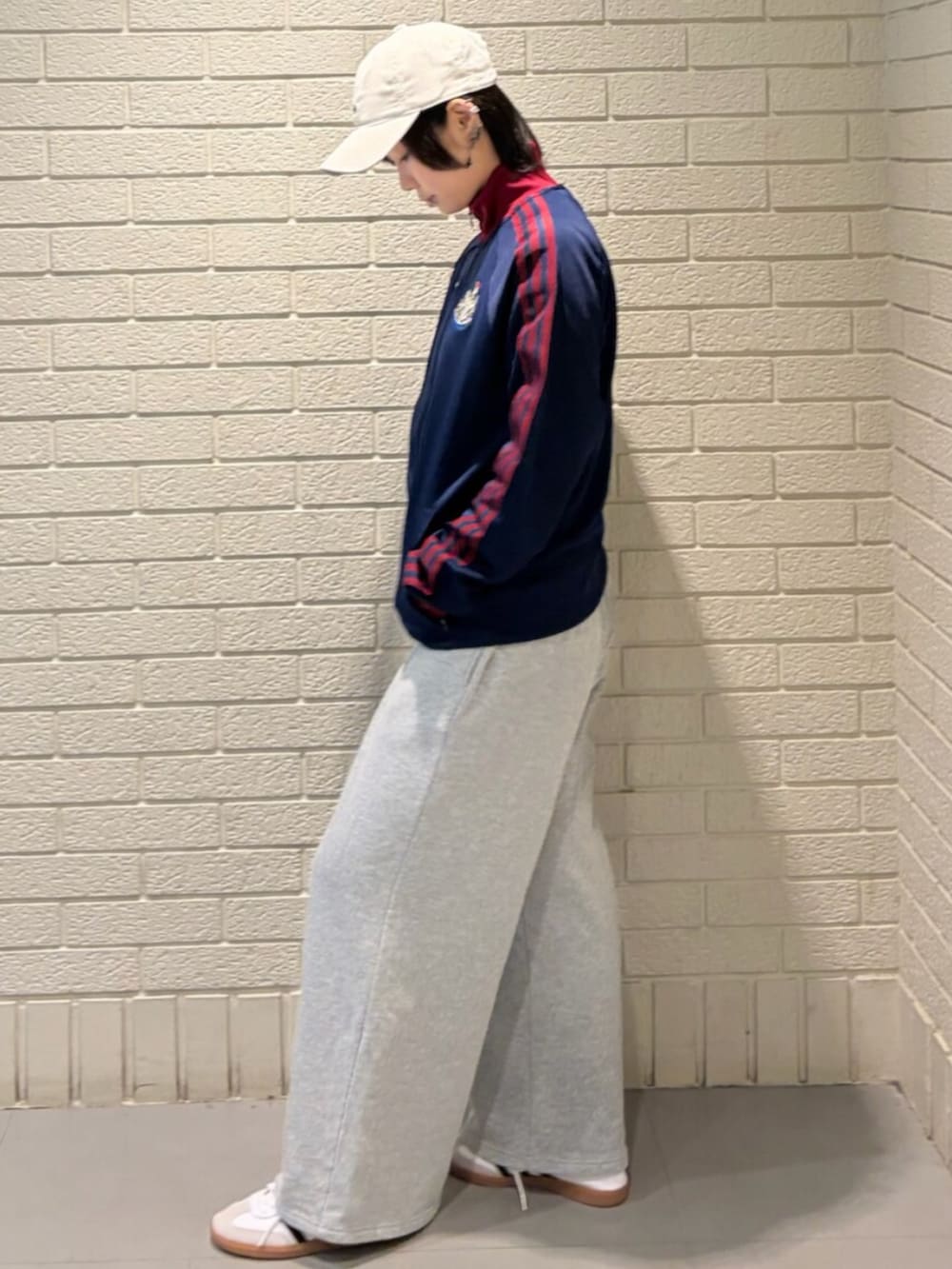 ホワイト系のシューズ、ブルー系のジャージ、ホワイト系のキャップを着用したレディースの春コーディネートの2枚目の写真