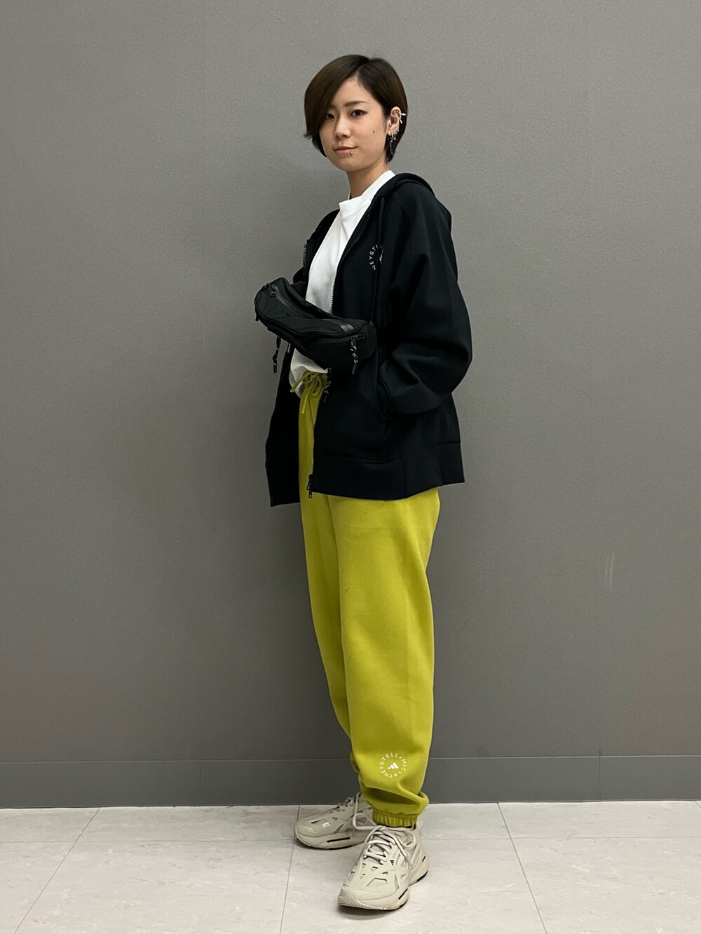 ブラック系のパーカー、ベージュ系のスニーカー、グリーン系のスウェットパンツを着用したレディースの冬コーディネートの2枚目の写真