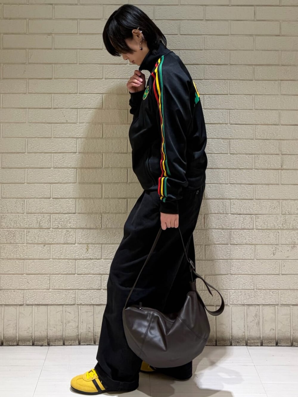 ブラック系のジャージ、ブラウン系のショルダーバッグ、イエロー系のスニーカーを着用したレディースの冬コーディネートの2枚目の写真