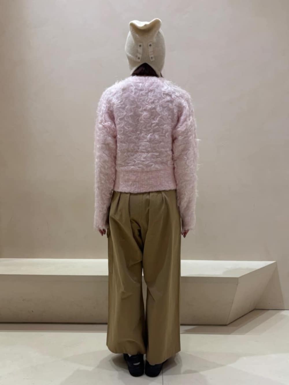 イエロー系のチノパンツ、ピンク系のカーディガン/ボレロ、ホワイト系のニットキャップ/ビーニーを着用したレディースの秋コーディネートの3枚目の写真