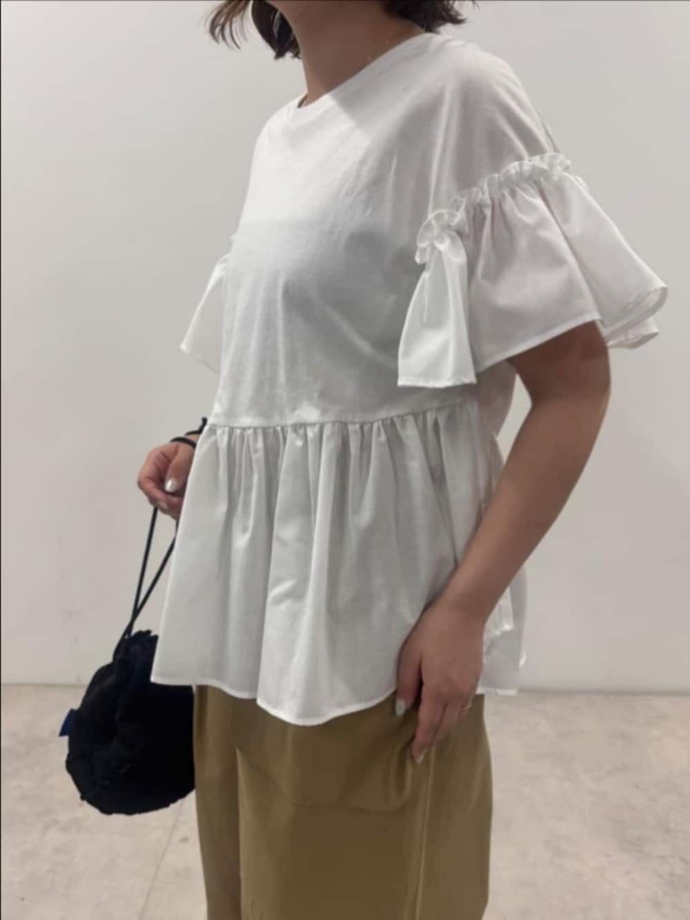 ホワイト系のTシャツ/カットソー、イエロー系のチノパンツ、ブラック系のハンドバッグを着用したレディースの夏コーディネートの2枚目の写真