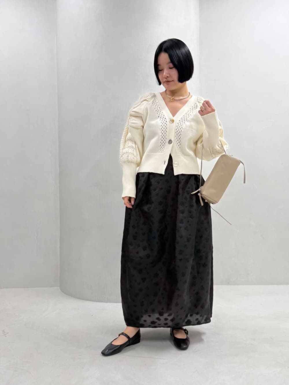 ホワイト系のカーディガン/ボレロ、ベージュ系のボストンバッグ、ブラック系のスカートを着用したレディースの冬コーディネートの2枚目の写真