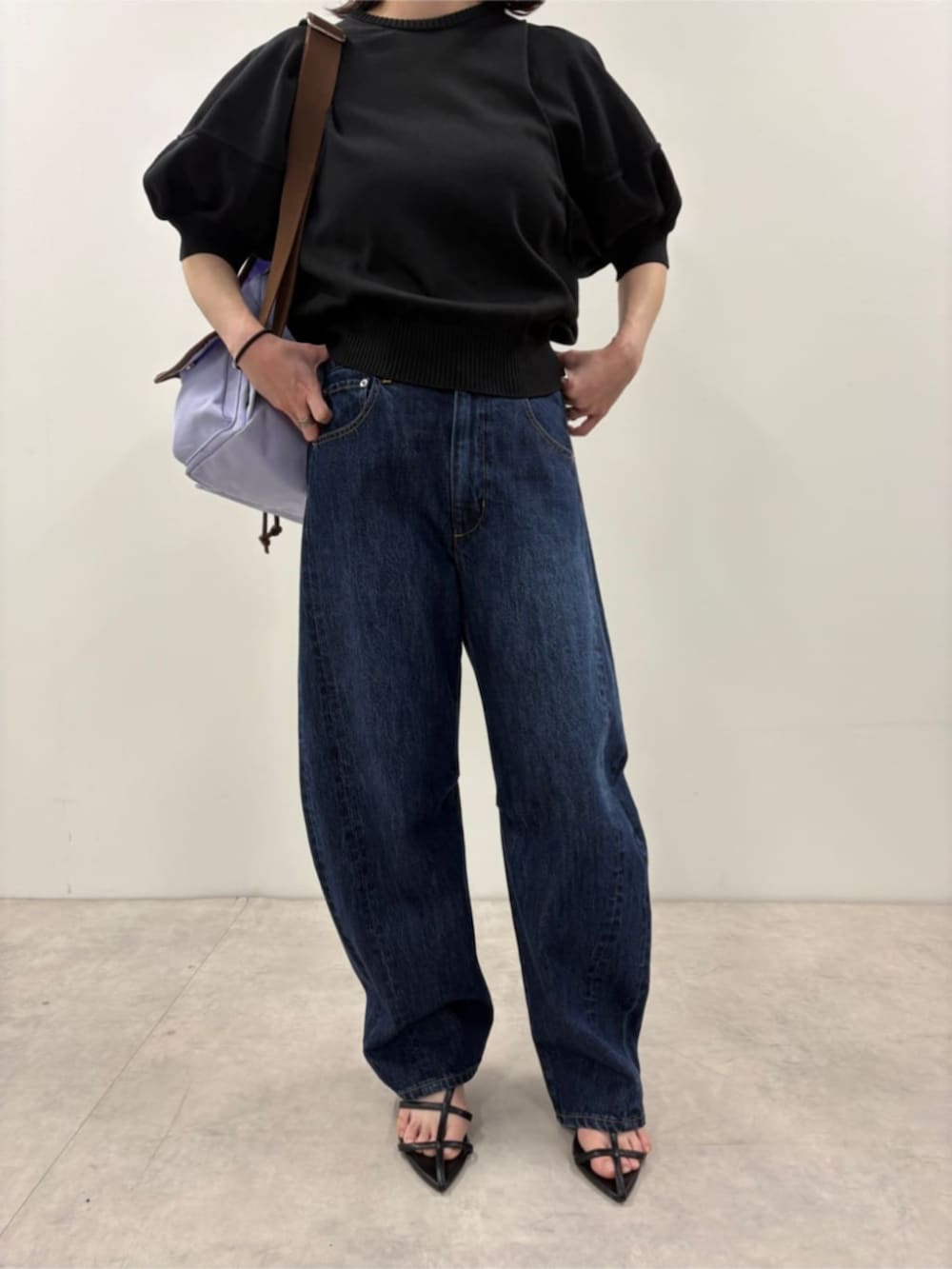 ブルー系のデニムパンツ、ブラック系のニット/セーター、パープル系のバックパック/リュックを着用したレディースの春コーディネートの7枚目の写真