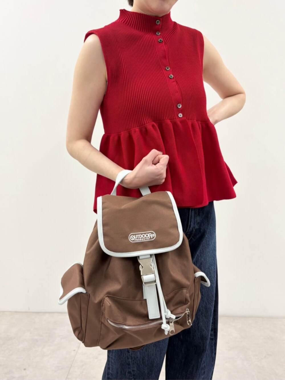 ブルー系のデニムパンツ、ブラウン系のバックパック/リュック、レッド系のベストを着用したレディースの春コーディネートの7枚目の写真