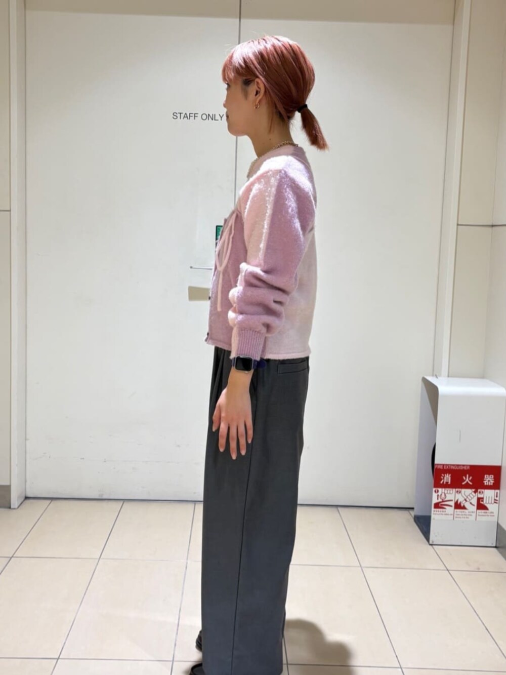 ピンク系のニット/セーター、ピンク系のチューブトップ、グレー系のスラックスを着用したレディースの冬コーディネートの2枚目の写真