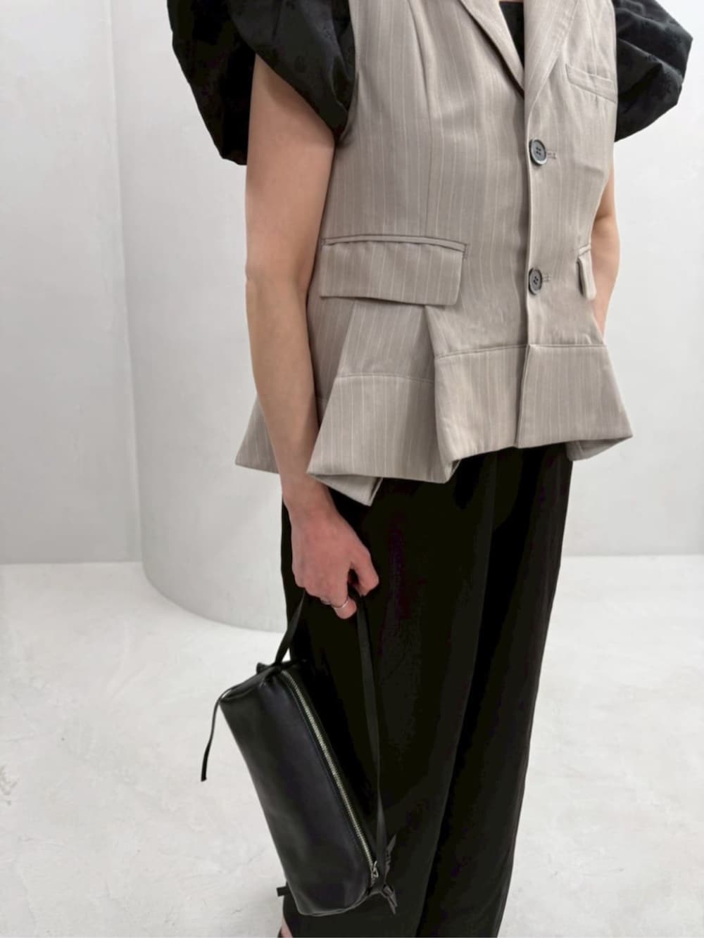 ブラック系のボストンバッグ、ブラック系のつなぎ/オールインワン、ベージュ系のベストを着用したレディースの冬コーディネートの6枚目の写真