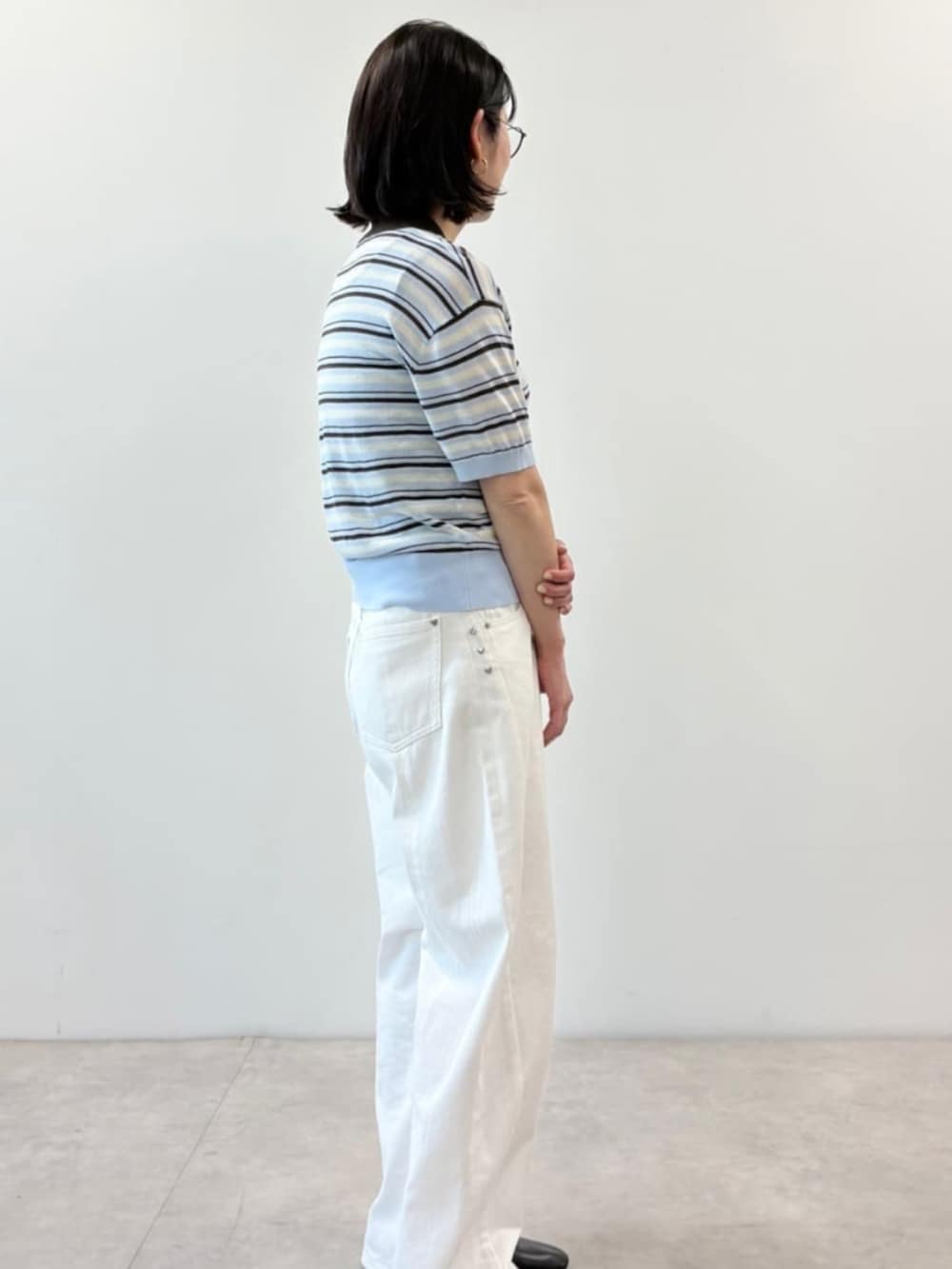 ホワイト系のデニムパンツ、ブルー系のポロシャツを着用したレディースの春コーディネートの2枚目の写真