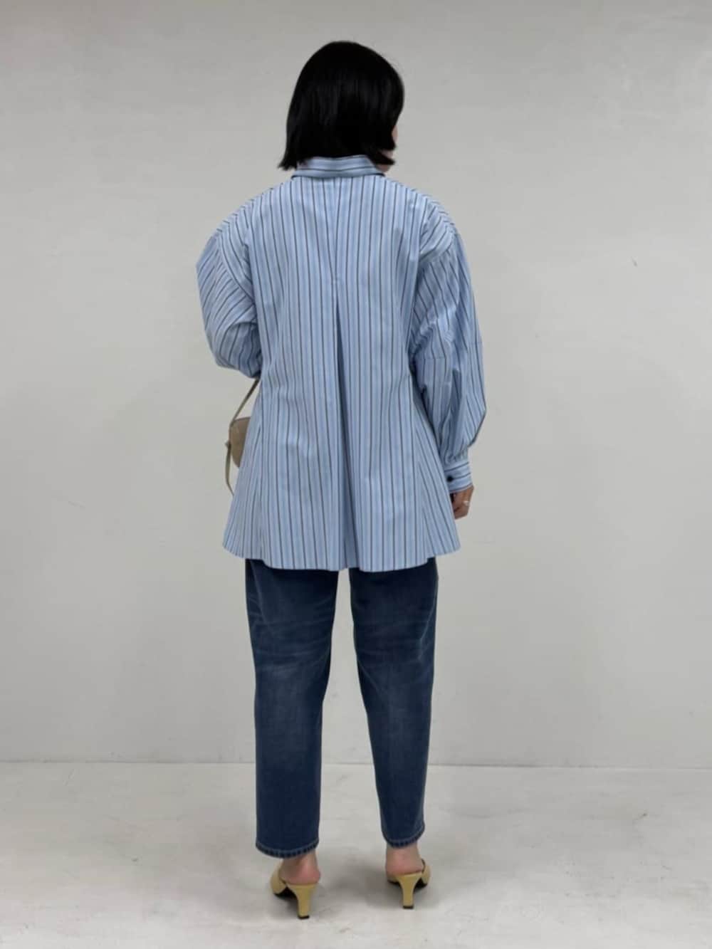 ブルー系のデニムパンツ、ブルー系のシャツ/ブラウス、ベージュ系のボストンバッグを着用したレディースの冬コーディネートの3枚目の写真