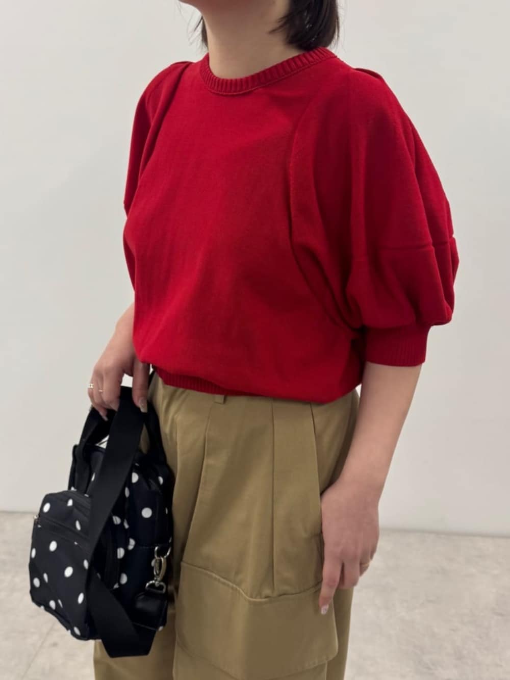 イエロー系のチノパンツ、レッド系のニット/セーター、その他のショルダーバッグを着用したレディースの春コーディネートの2枚目の写真