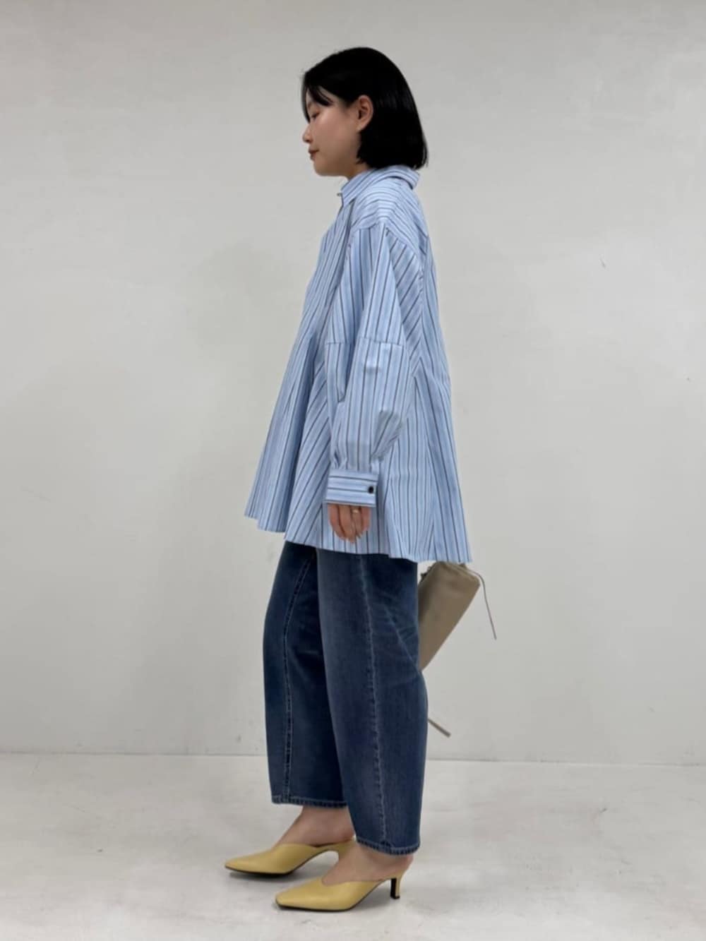 ブルー系のデニムパンツ、ブルー系のシャツ/ブラウス、ベージュ系のボストンバッグを着用したレディースの冬コーディネートの2枚目の写真