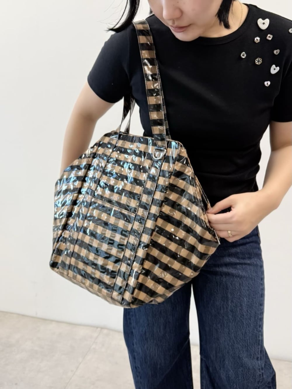 ブラック系のTシャツ/カットソー、ベージュ系のトートバッグ、ブルー系のデニムパンツを着用したレディースの春コーディネートの3枚目の写真