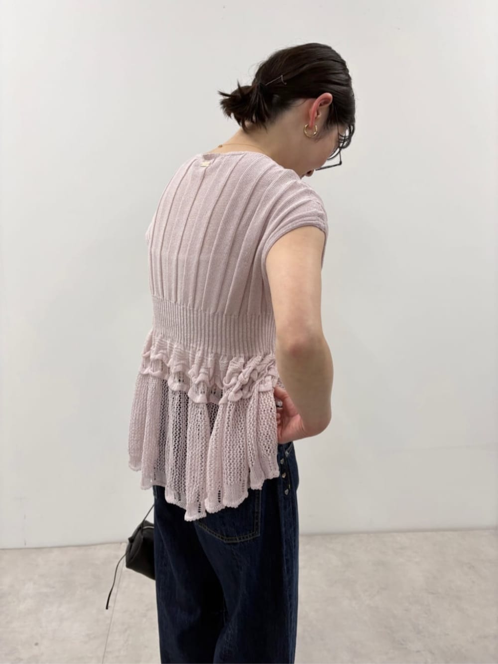 ブラック系のボストンバッグ、ブルー系のデニムパンツ、パープル系のニット/セーターを着用したレディースの春コーディネートの8枚目の写真