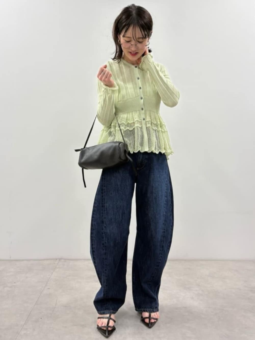 ブラック系のボストンバッグ、ブルー系のカーディガン/ボレロ、ブルー系のデニムパンツを着用したレディースの春コーディネートの2枚目の写真