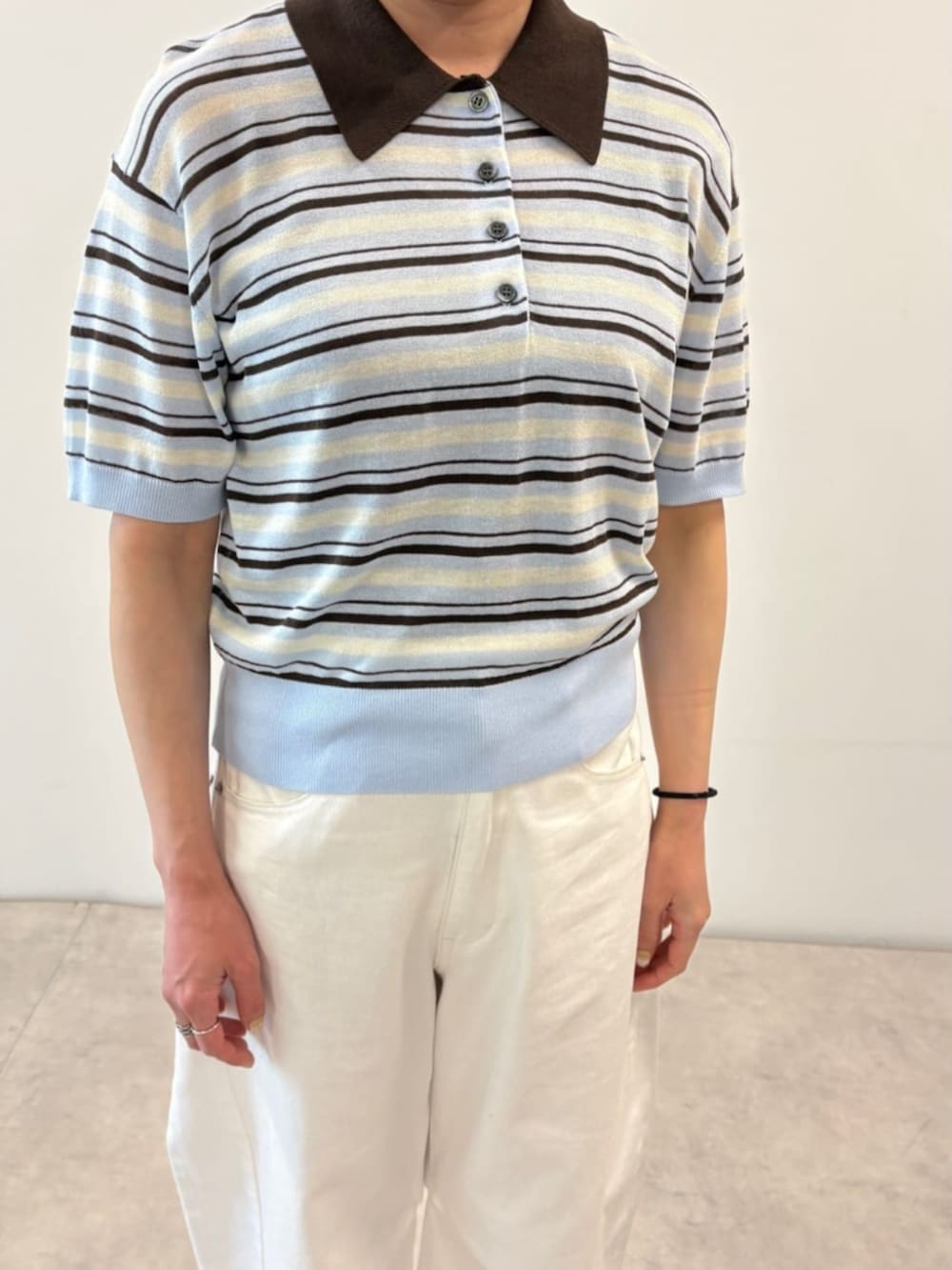 ホワイト系のデニムパンツ、ブルー系のポロシャツを着用したレディースの春コーディネートの3枚目の写真