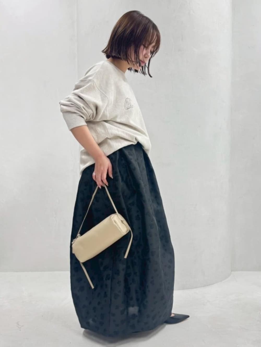 ベージュ系のボストンバッグ、ホワイト系のスウェット、ブラック系のスカートを着用したレディースの春コーディネートの2枚目の写真