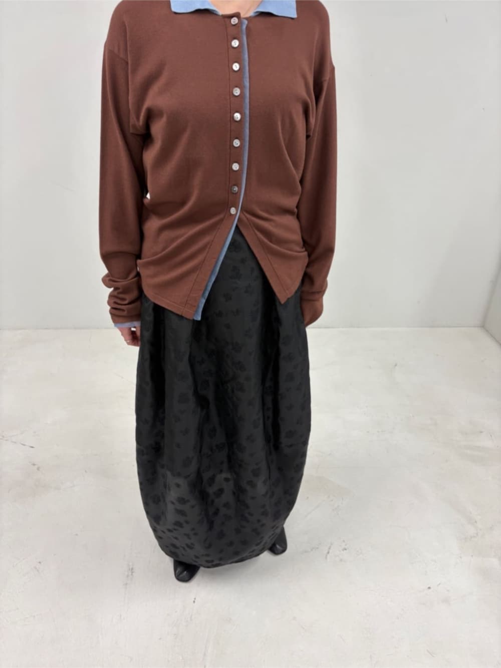 ブラウン系のカーディガン/ボレロ、ブラック系のスカートを着用したレディースの冬コーディネートの7枚目の写真