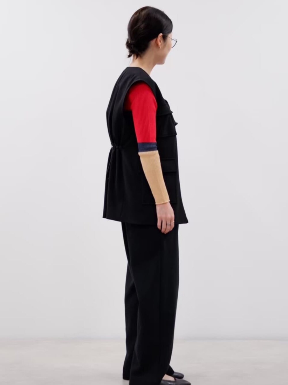 ブラック系のベスト、レッド系のニット/セーター、ブラック系のつなぎ/オールインワンを着用したレディースの秋コーディネートの4枚目の写真