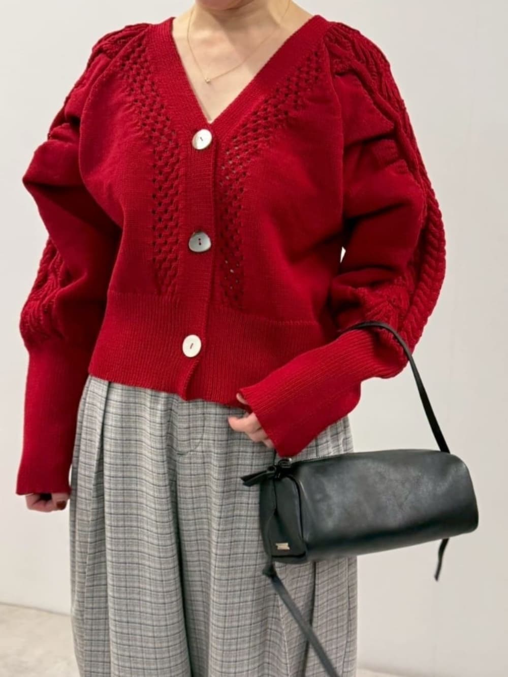 ブラック系のローファー、ブラック系のボストンバッグ、レッド系のカーディガン/ボレロを着用したレディースの冬コーディネートの4枚目の写真