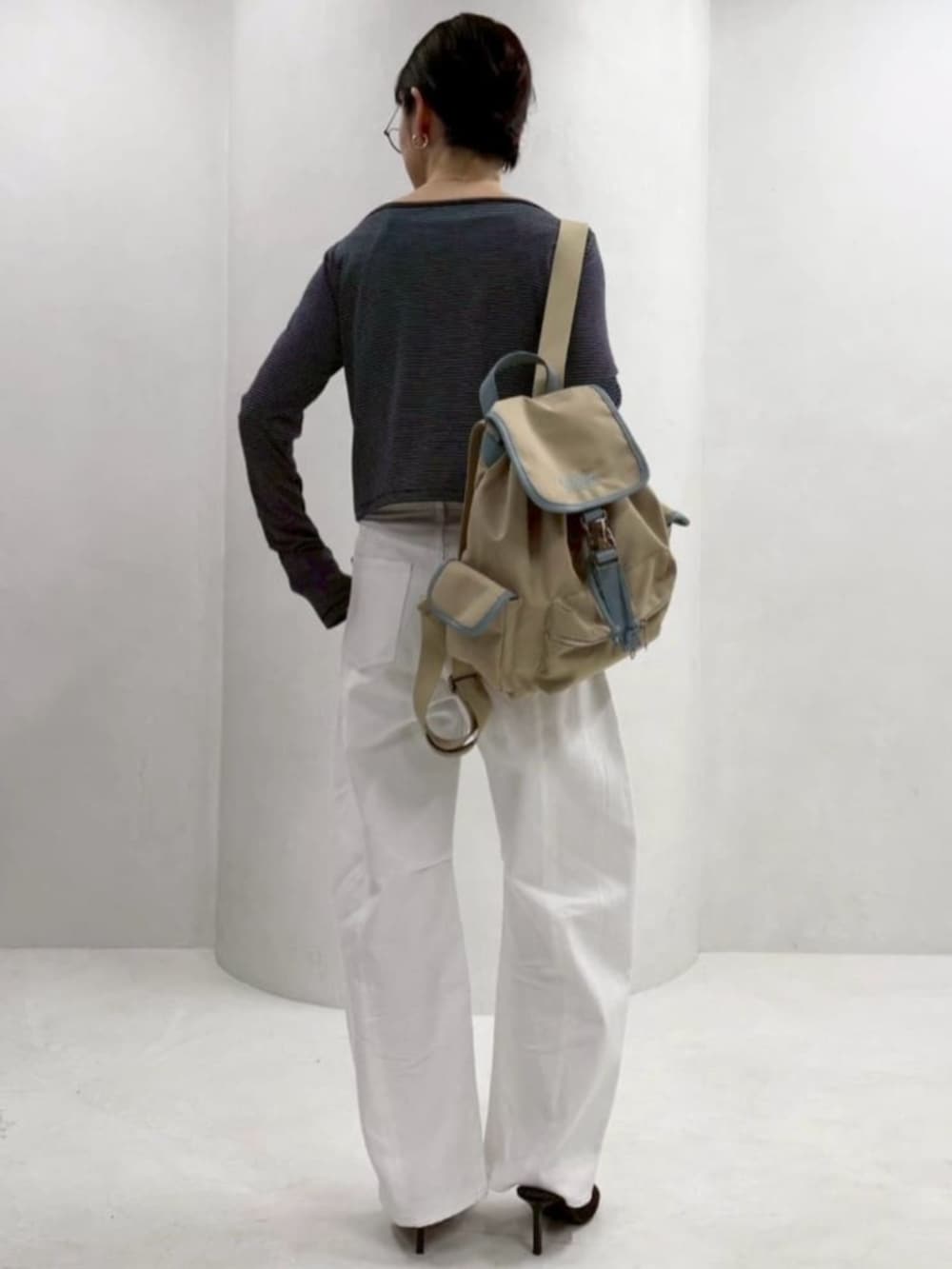 ベージュ系のバックパック/リュック、ホワイト系のデニムパンツ、ブルー系のカーディガン/ボレロを着用したレディースの春コーディネートの4枚目の写真